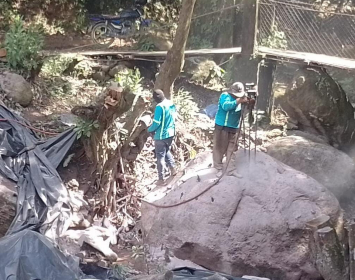 Vista general de una obra con un bloque de roca y trabajadores